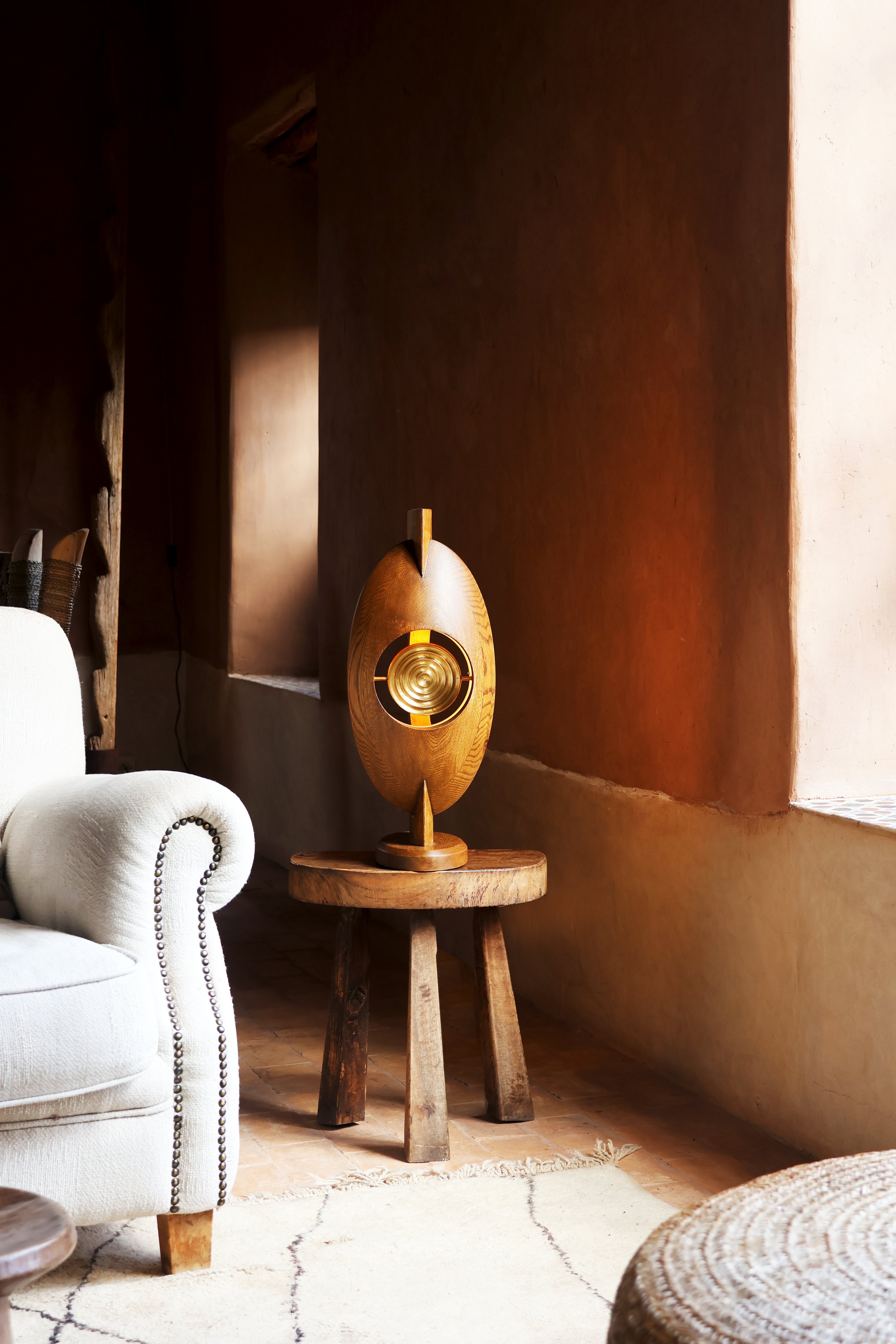 Lamp on stool against a brown wall and chair