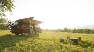 Camper van in a field with a camp set up