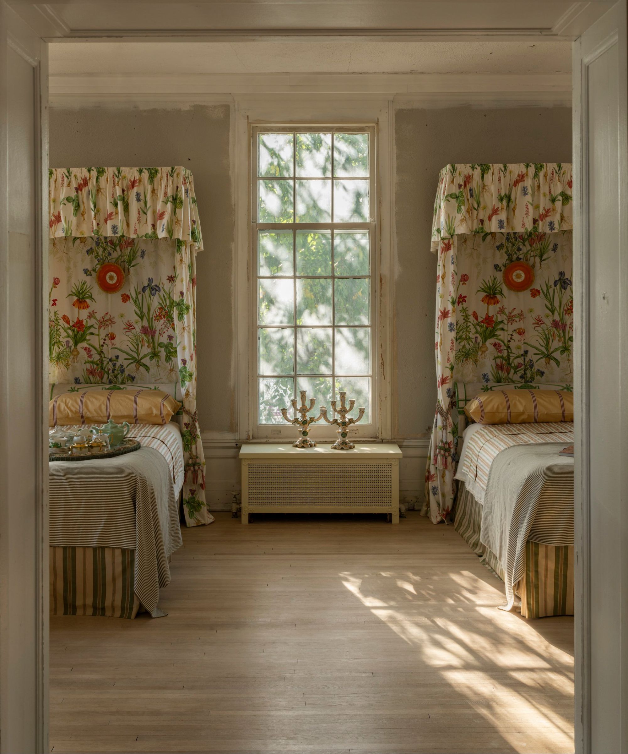 a twin bedroom in a historic building with worn plaster walls and floral canopies