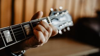 Capturing a musician's hand pressing guitar strings with natural lighting.