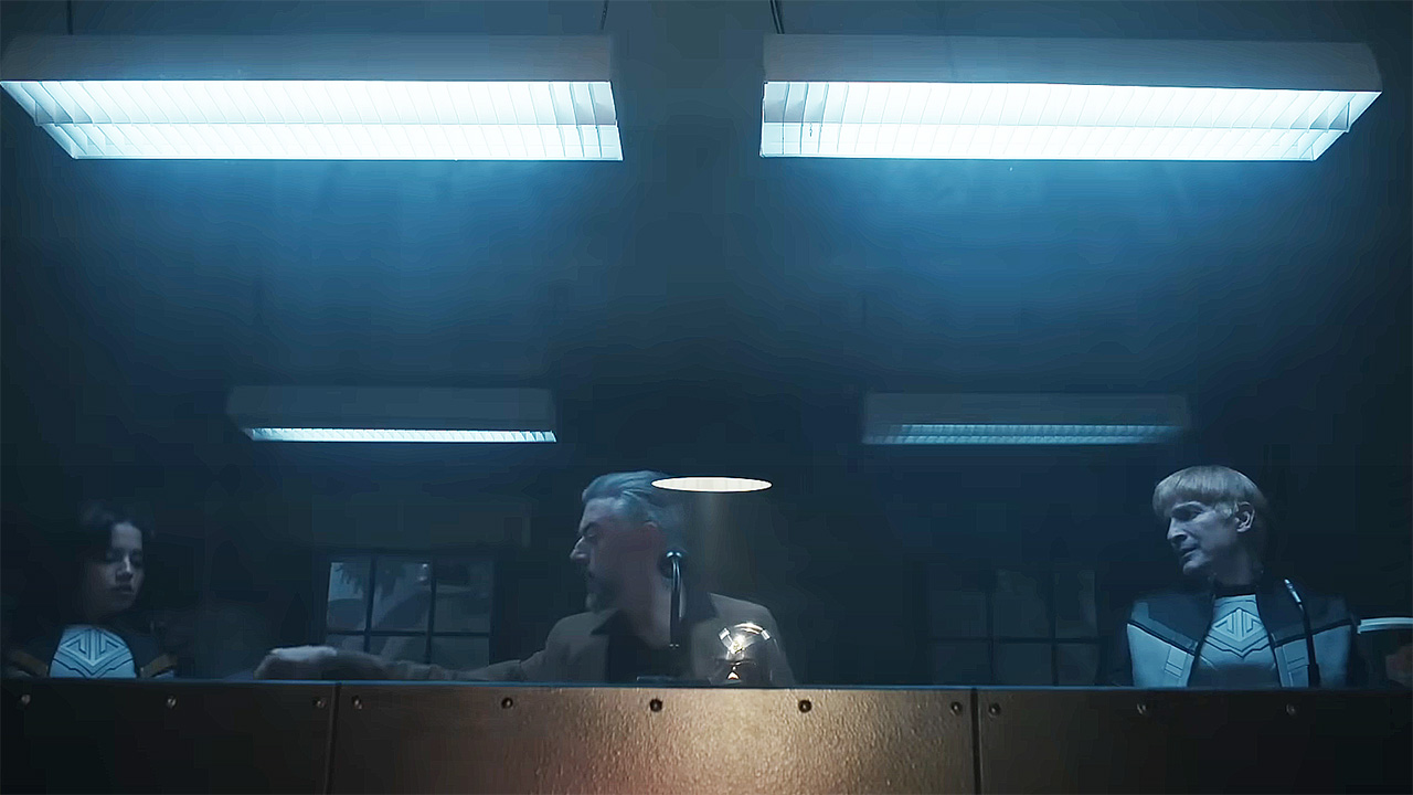 Hawkgirl, Maxwell Lord, and Guy Gardner sitting behind some Perspex glass in Peacemaker season 2