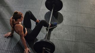 woman sat by a barbell