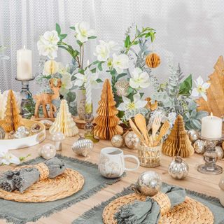 Festive table in gold and white with placemats and christmas trees