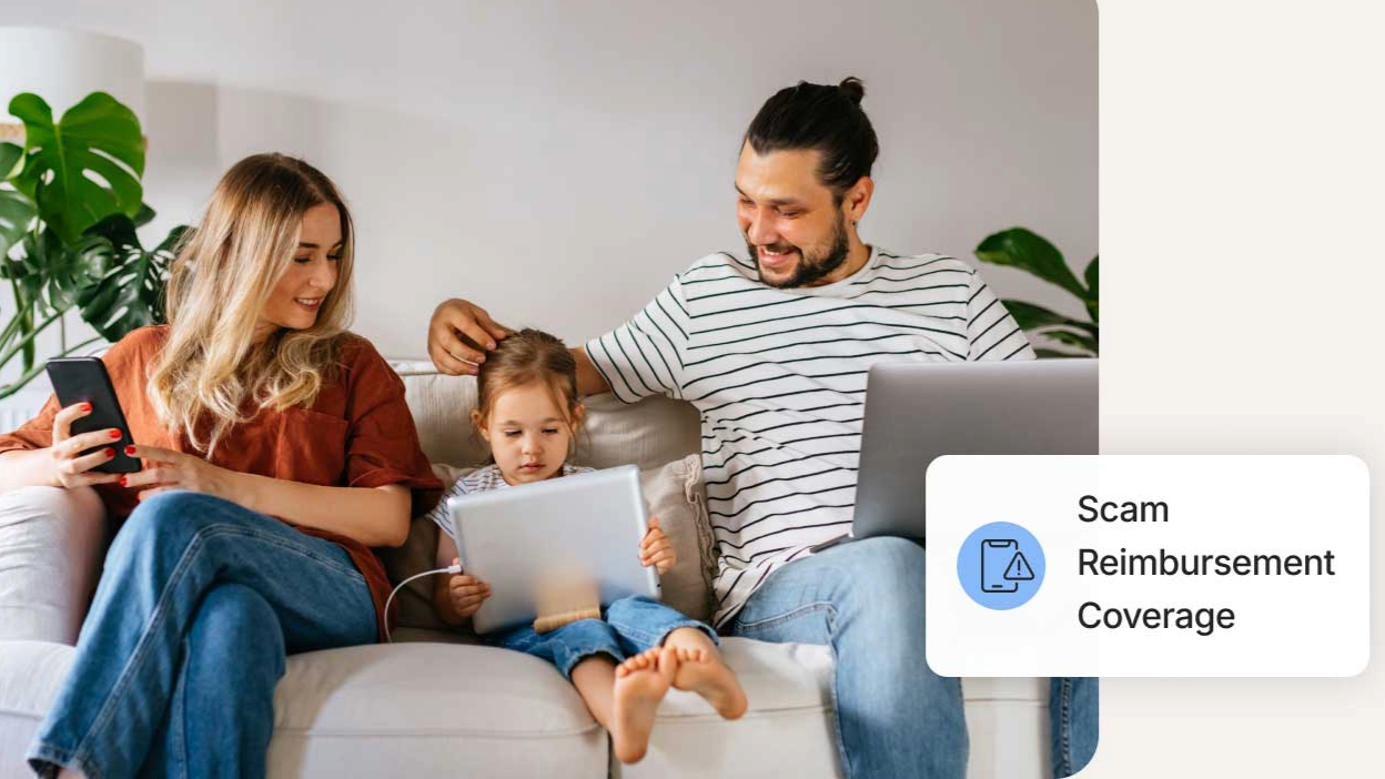 A family on the couch, each with a piece of technology. The mom with a phone, the child with a tablet, and the father with a laptop. In the corner, we see the words, "Scam reimbursement coverage."