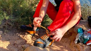 Man tying Scarpa Instinct Lace climbing shoes