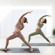 Two women practice yoga side by side after downloading one of the best yoga apps
