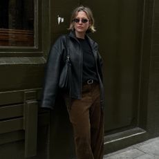 Influencer @alexisforeman wears brown corduroy trousers with a black leather jacket and black leather loafers.