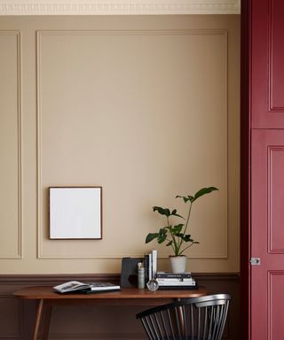 A dusty taupe wall with a deep, dusky red cabinet beside a black desk and chair