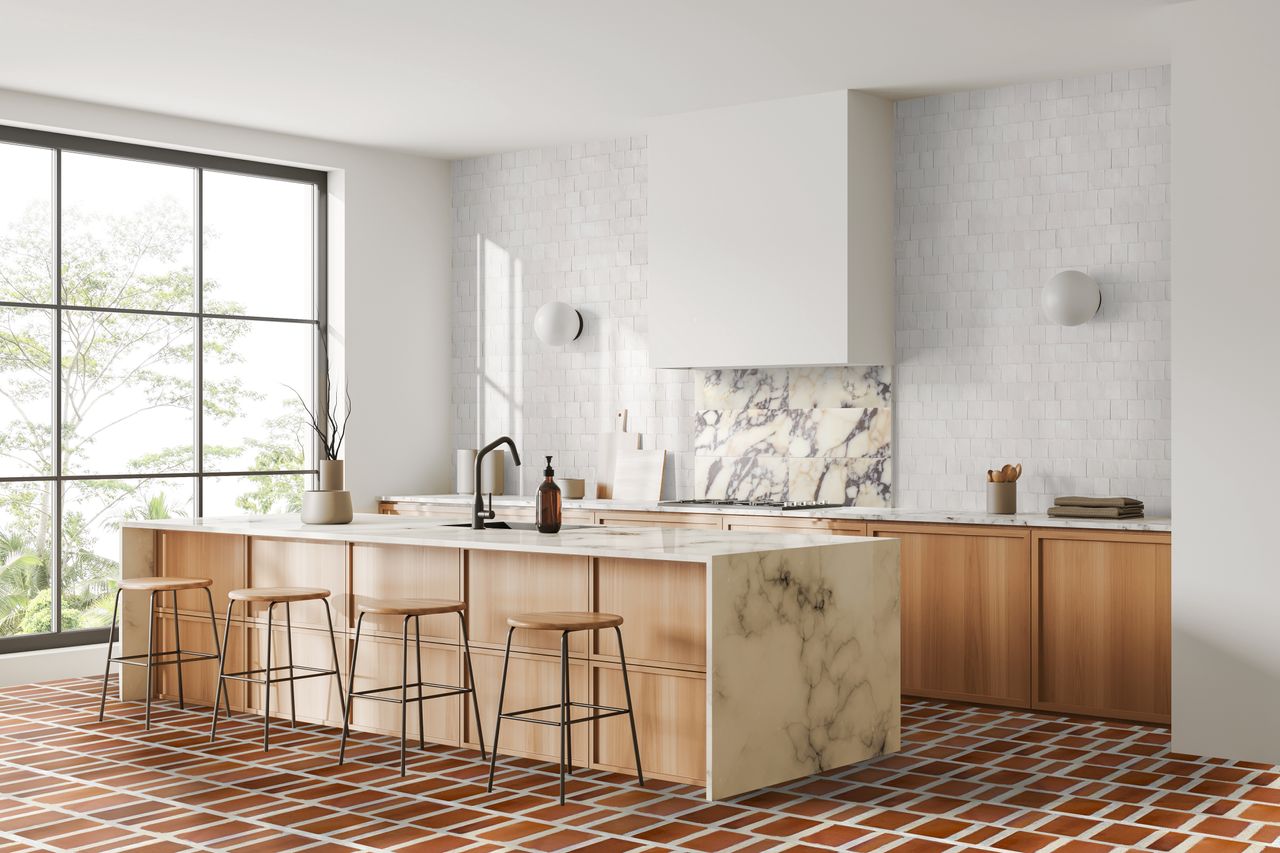 A kitchen with terracotta style tiles on the floor and white textured gloss tiles up the sink wall