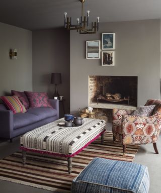 A cozy grey living room snug with stripe upholstered ottoman, stripe rug and patterned armchair