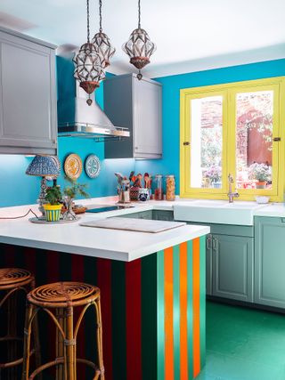 A brightly coloured small kitchen with a striped island