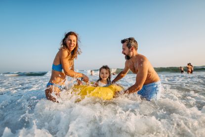 Young family with little children enjoying time at sea, having fun together.