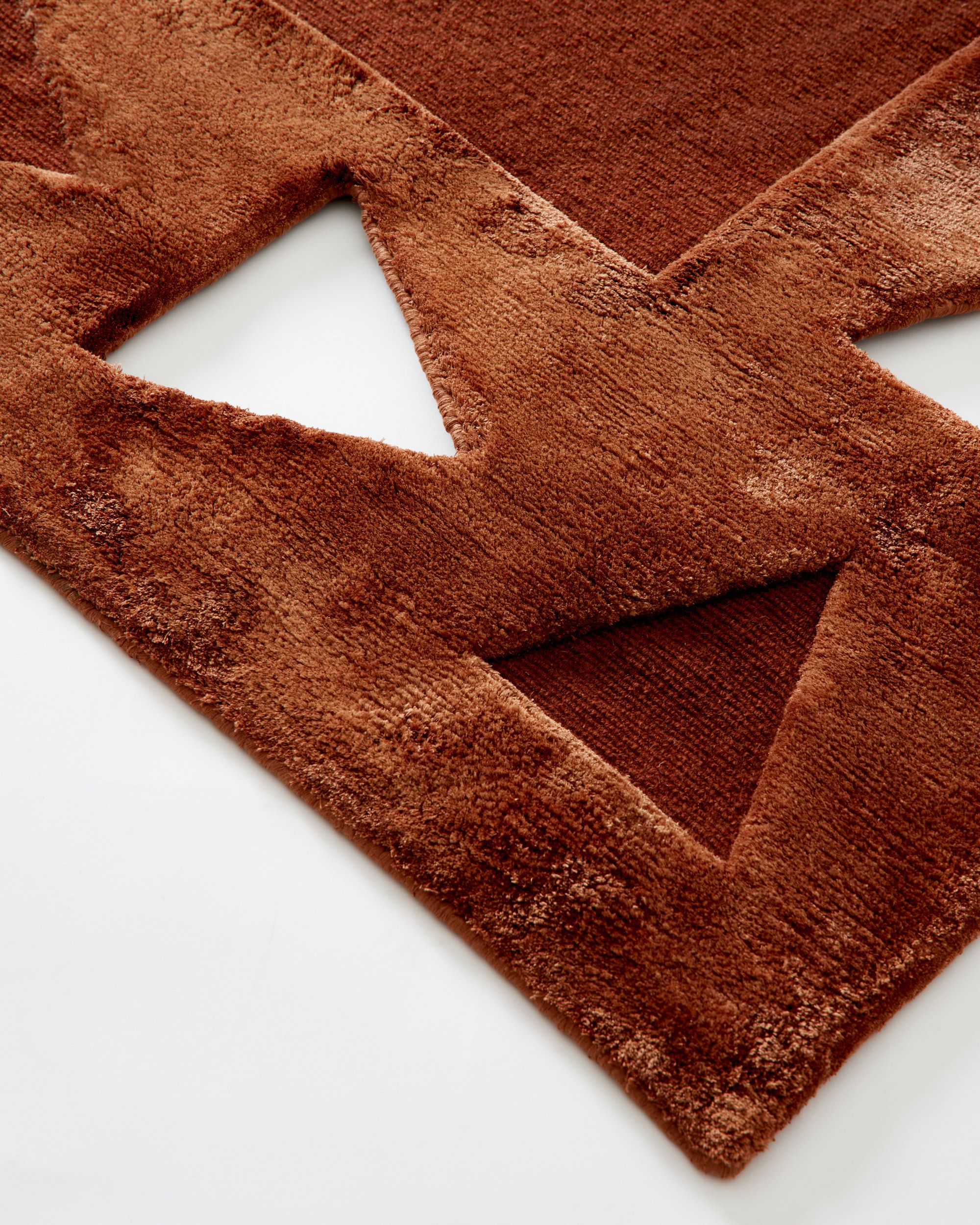 A brown rug with triangles cut out of the textile for graphic effect.