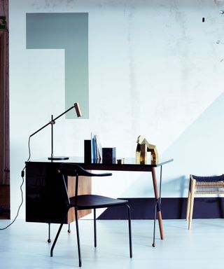 black desk and chair in cool toned room with gold lamp