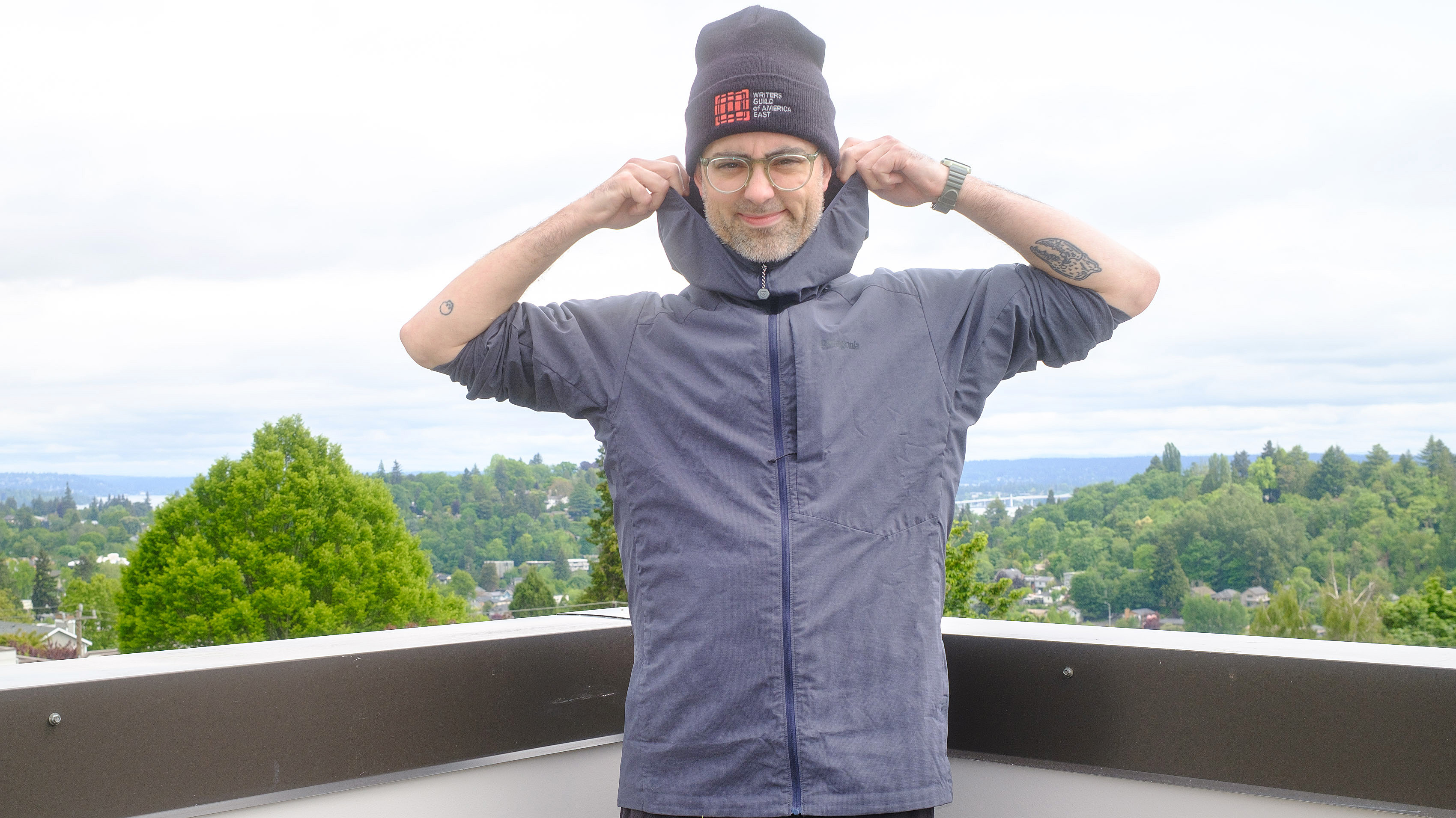 Senior writer Dan Bracaglia wearing the Patagonia Nano-Air Ultralight in grey/blue on the roof of his home in Seattle, Washington with trees and overcast skies in the distance