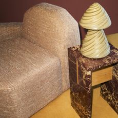 The Morra ceramic table lamp on a red marble side table and a modular chair from the H&M Home x Kelly Wearstler collection