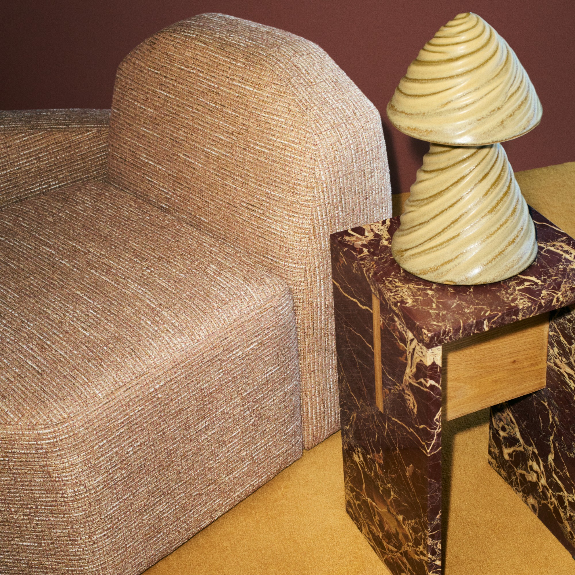 The Morra ceramic table lamp on a red marble side table and a modular chair from the H&amp;M Home x Kelly Wearstler collection