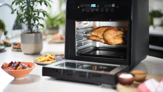 Air fryer oven with door open cooking a chicken to show why how to clean an air fryer is important