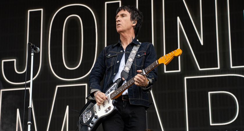Johnny Marr plays a Fender Jaguar with lipstick pickups onstage, with his name in bold behind him.