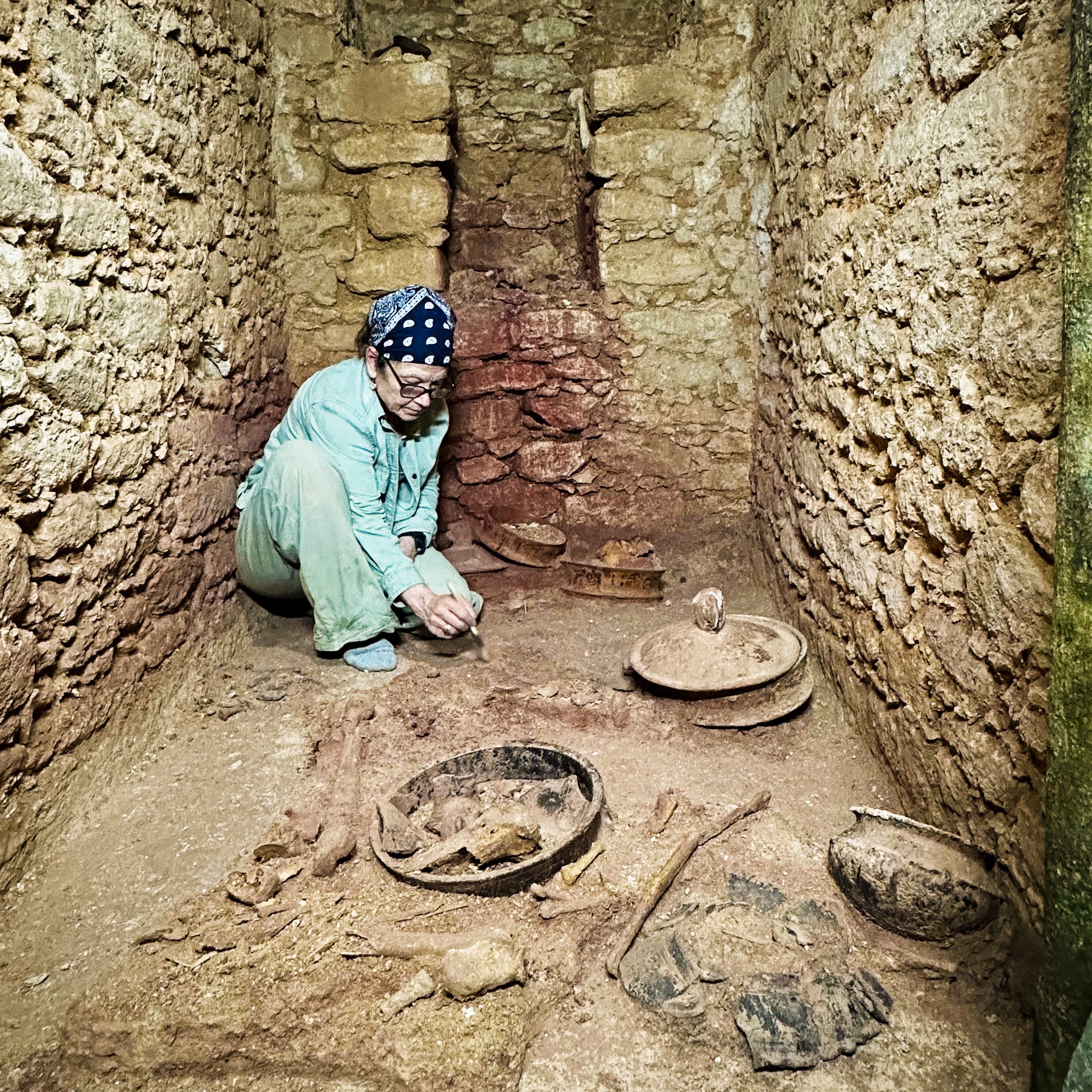 an archaeologist excavates goods inside a stone tomb
