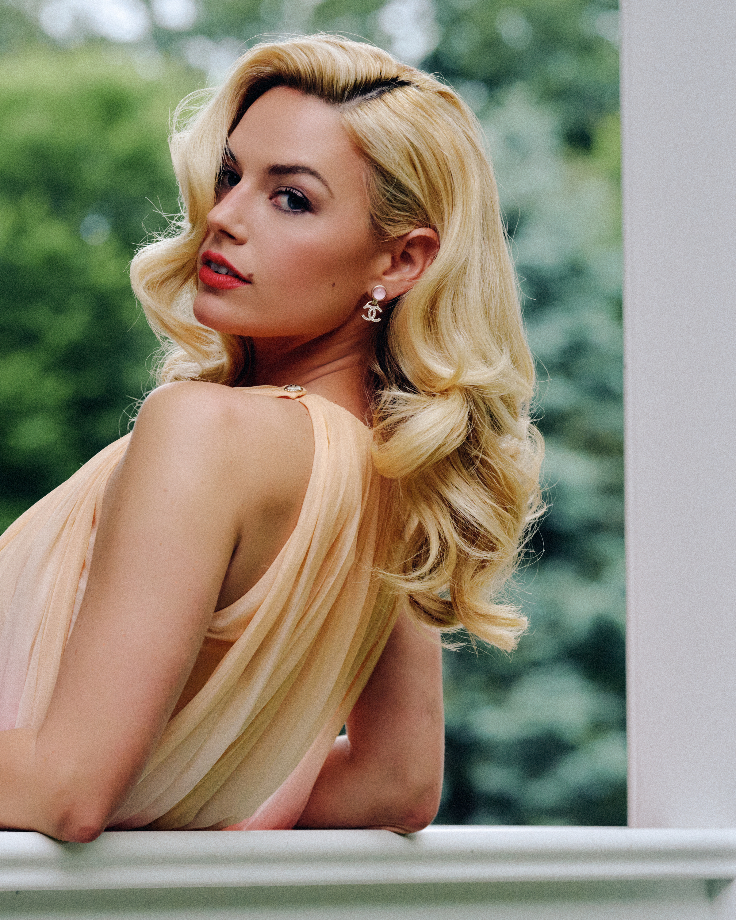 Ashe poses on a balcony wearing a Chanel dress and Chanel earrings
