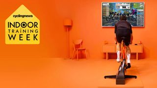 A man using Zwift on a turbo trainer, in a completely orange room, with the Cyclingnews Indoor Training Week badge overlaid