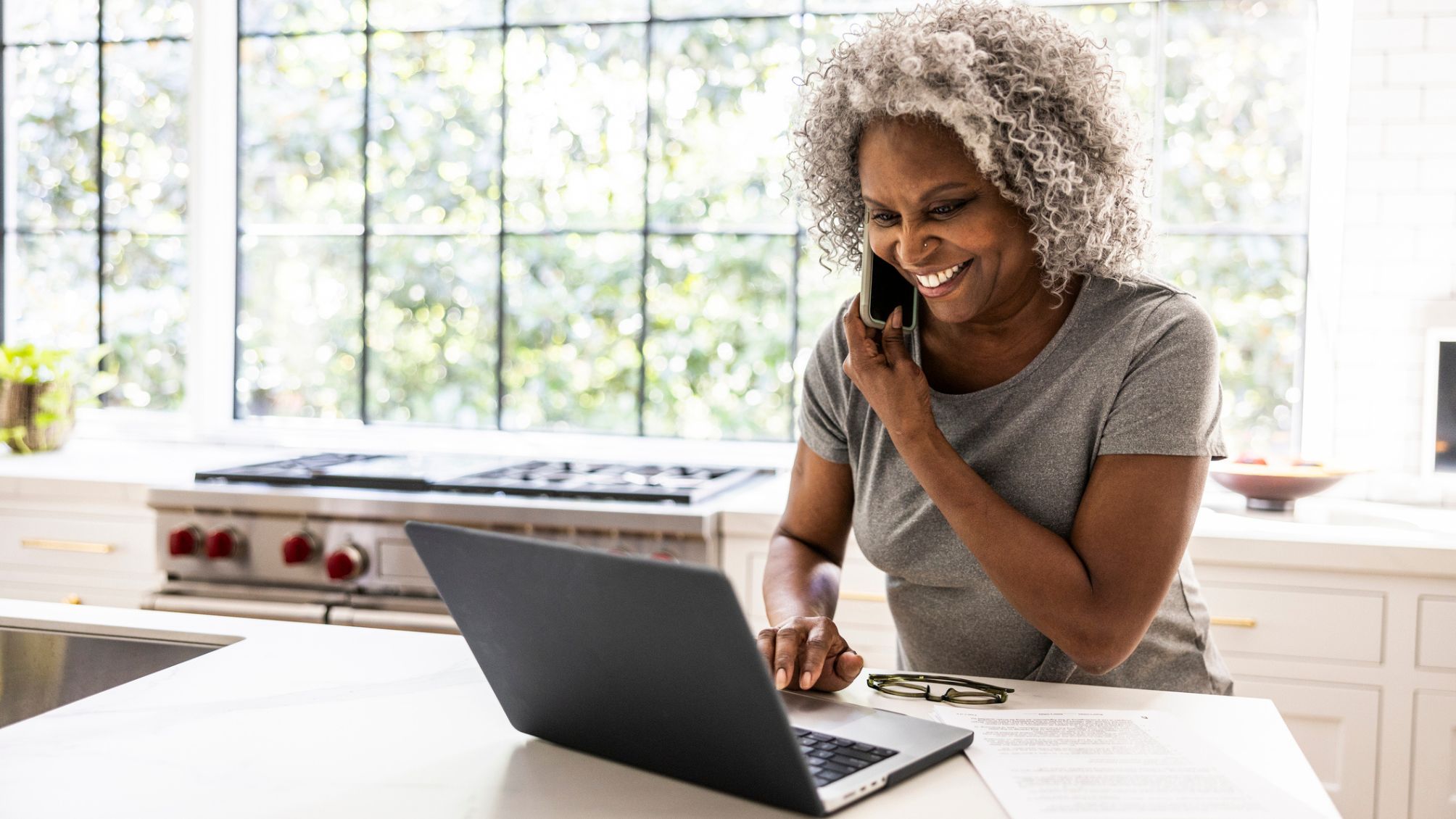 A woman talking on the phone while looking at her laptop