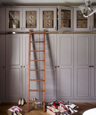 A row of taupe built-in cabinets with a wooden ladder.