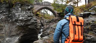 Man hiking while wearing a Mission Workshop Hauser 10L hydration pack, looking at a bridge