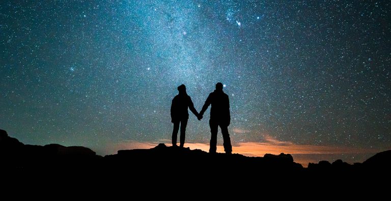 Couple standing beneath a big sky of stars