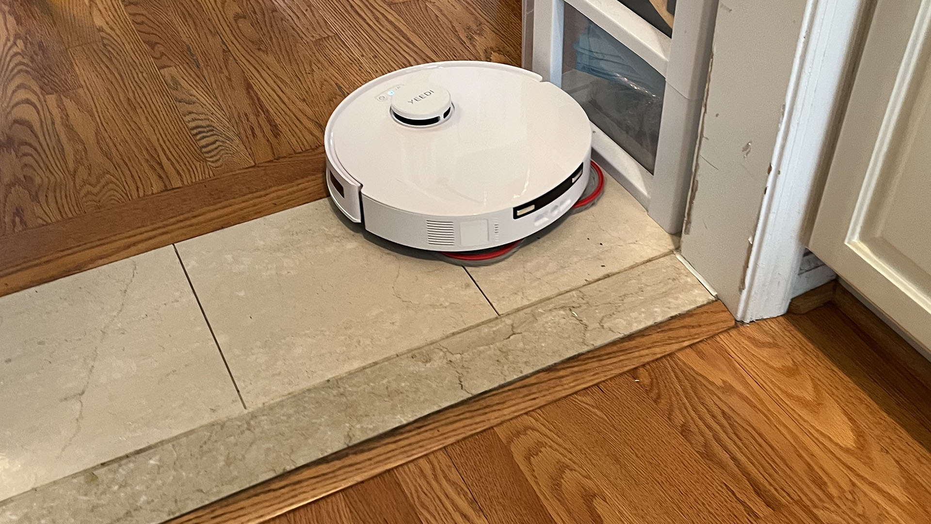 Yeedi M12 Ultra Plus robot vacuum with mop pad extended, near the corner of a room