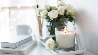 White room interior decor with burning hand-made candle and bouq - stock photo