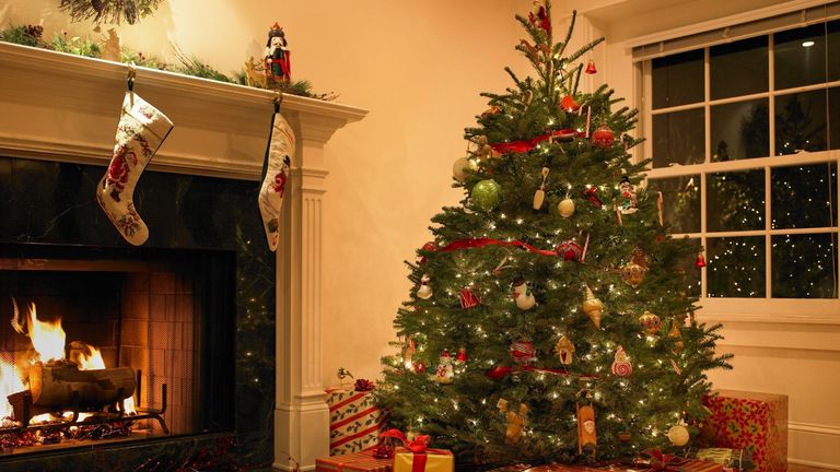 An example of how to decorate a Christmas tree pictured in a living room with an open fire