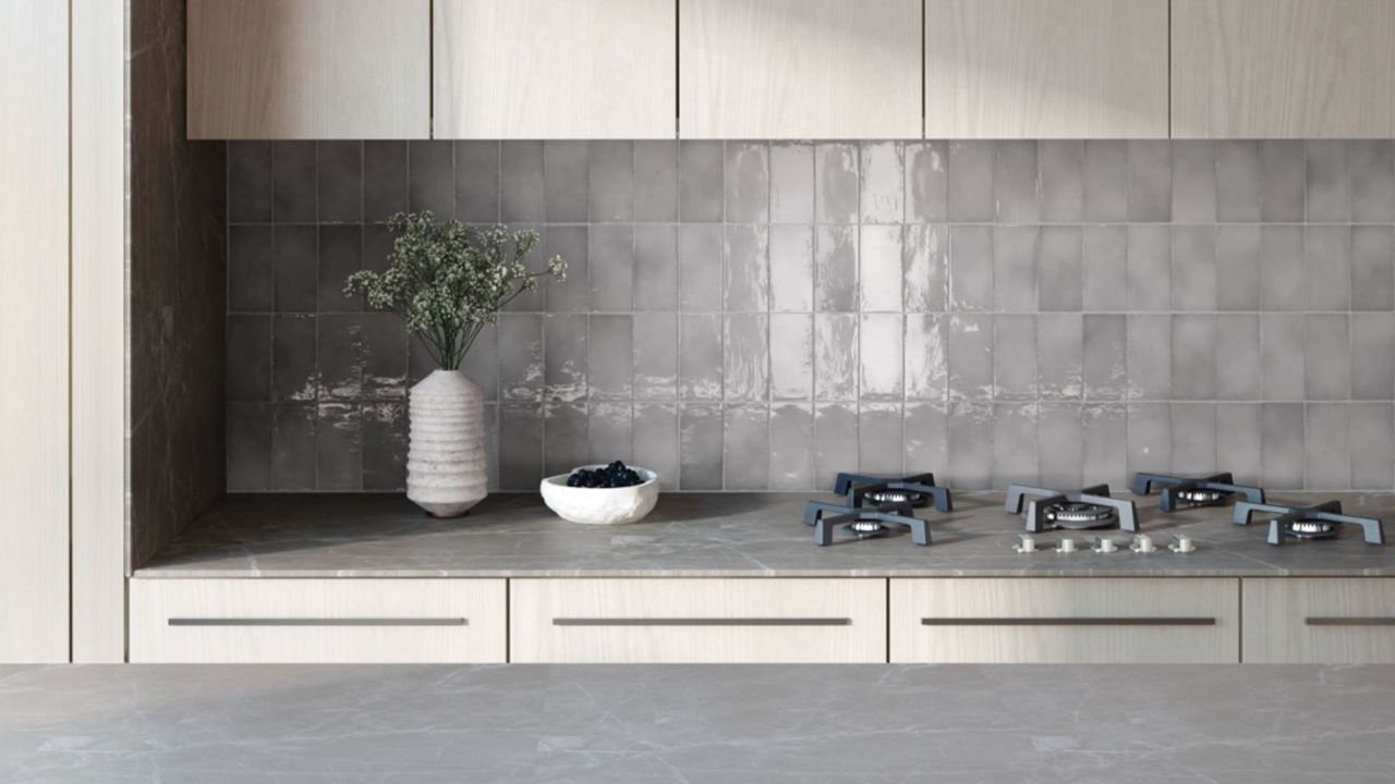 A biult in countertop gas stove in front of a white tiled kitchen backsplash 