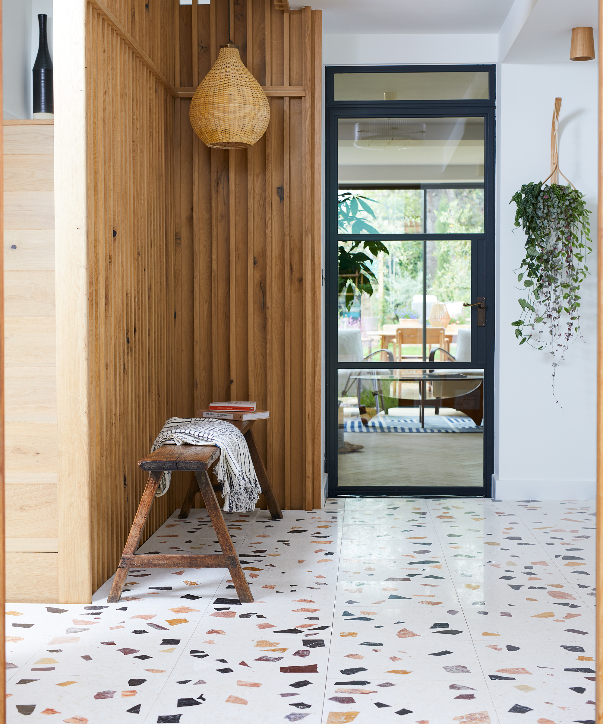 hallway with terrazzo floor tiles, wooden walls and seating bench