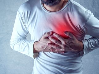 Man holding his hands over his chest as if experiencing heart attack