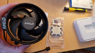 AMD Ryzen 5 8600G review image showing the processor in its packaging next to the included cooler