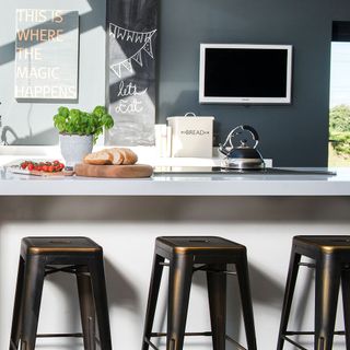 kitchena area with grey wall and white counter with black chair