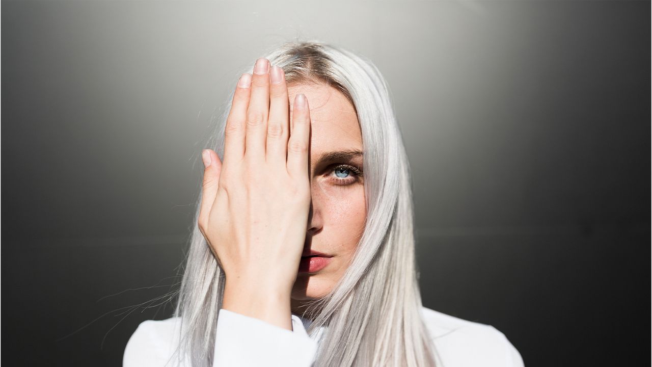 Portrait of serious young woman covering one eye - stock photo