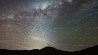 bright streaks of light crisscross through a night sky
