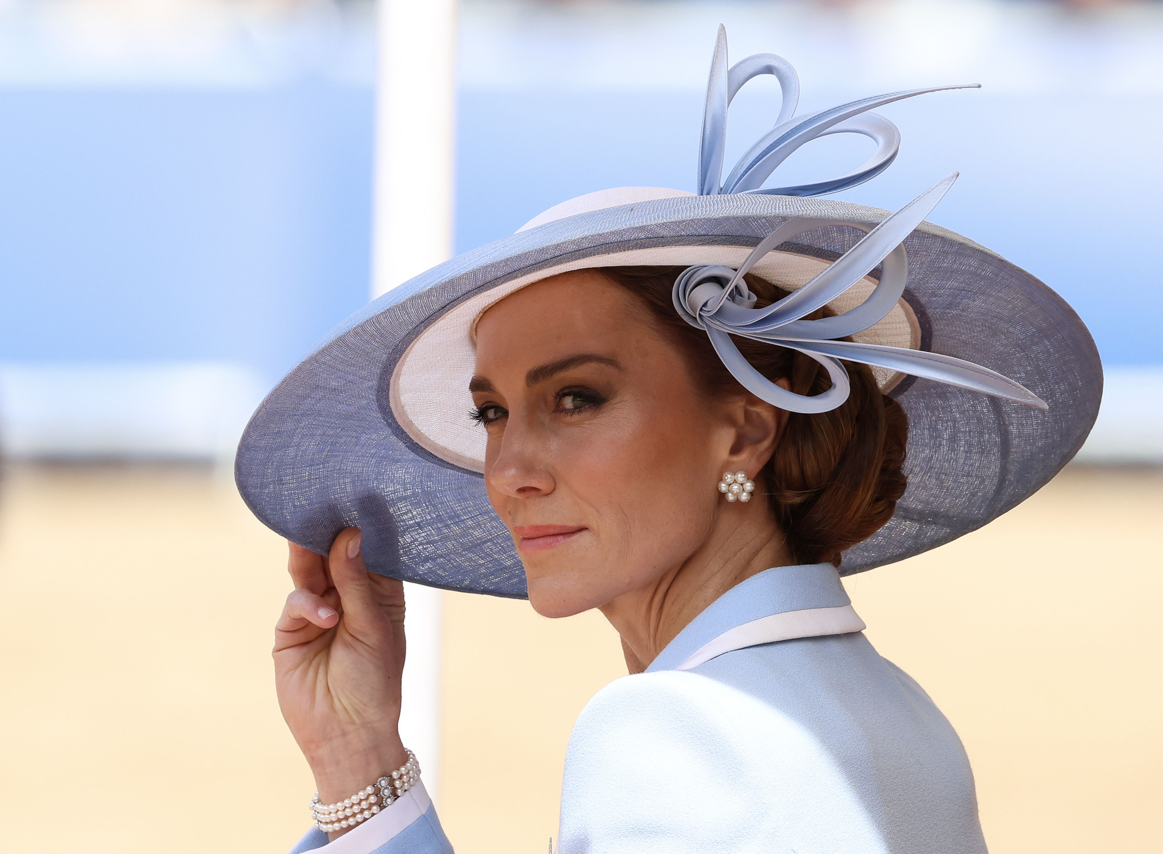 Princess Kate holding the brim of her blue hat at Trooping the Colour