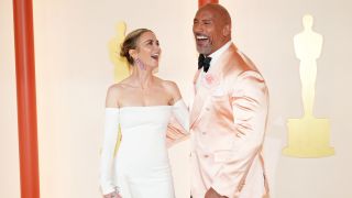 Dwayne Johnson and Emily Blunt laughing together on the 2023 Oscars red carpet