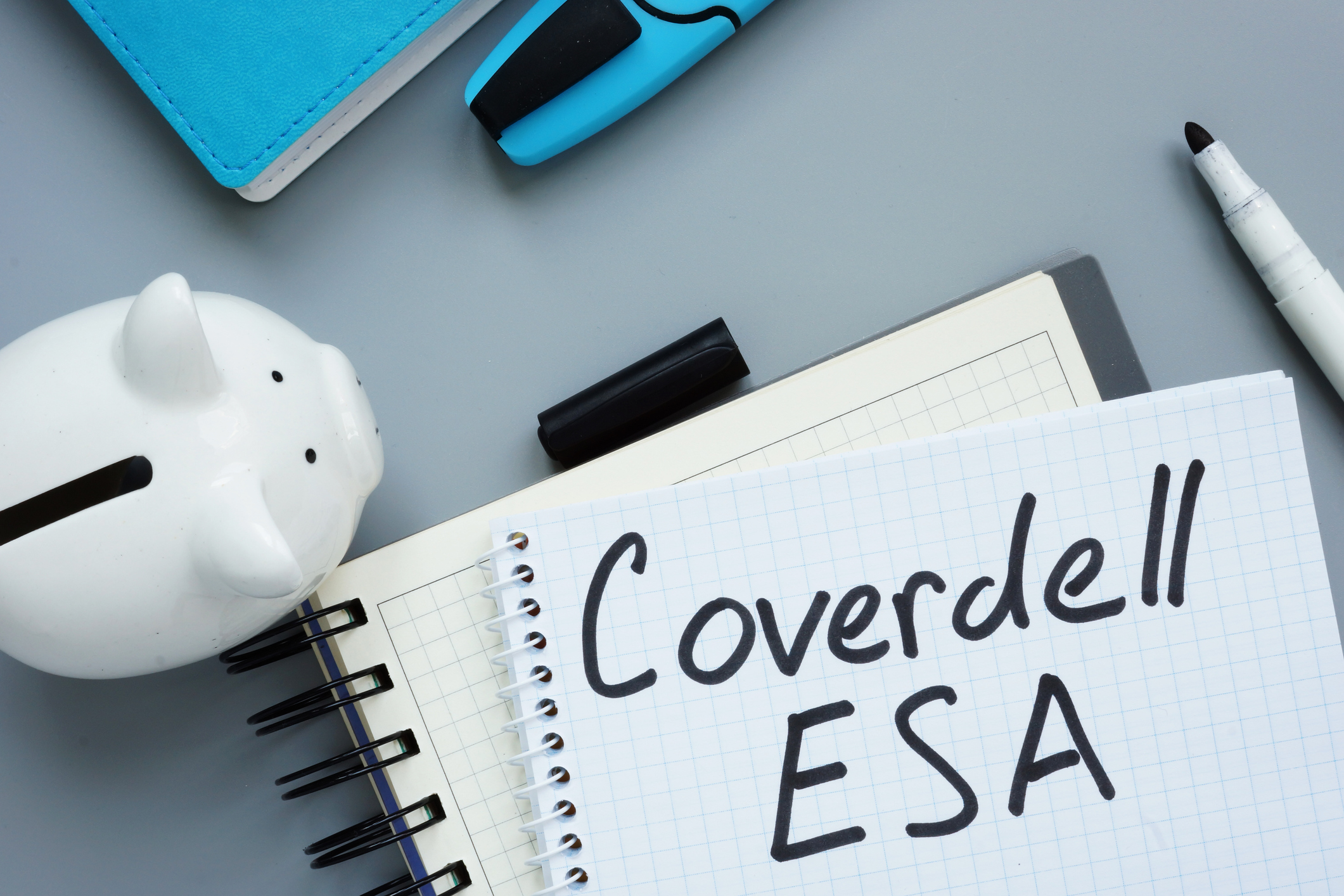 "Coverdell ESA" written on notebook with piggy bank and various desk supplies