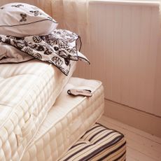 Three mattress stacked on top of each other with white and black bedding folded up on top