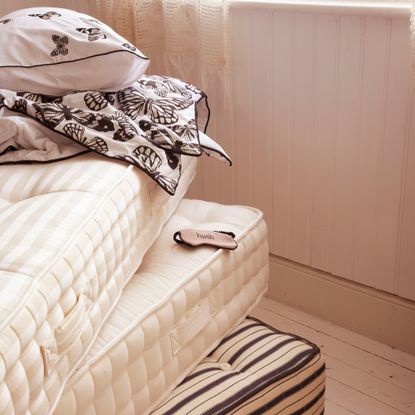 Three mattress stacked on top of each other with white and black bedding folded up on top