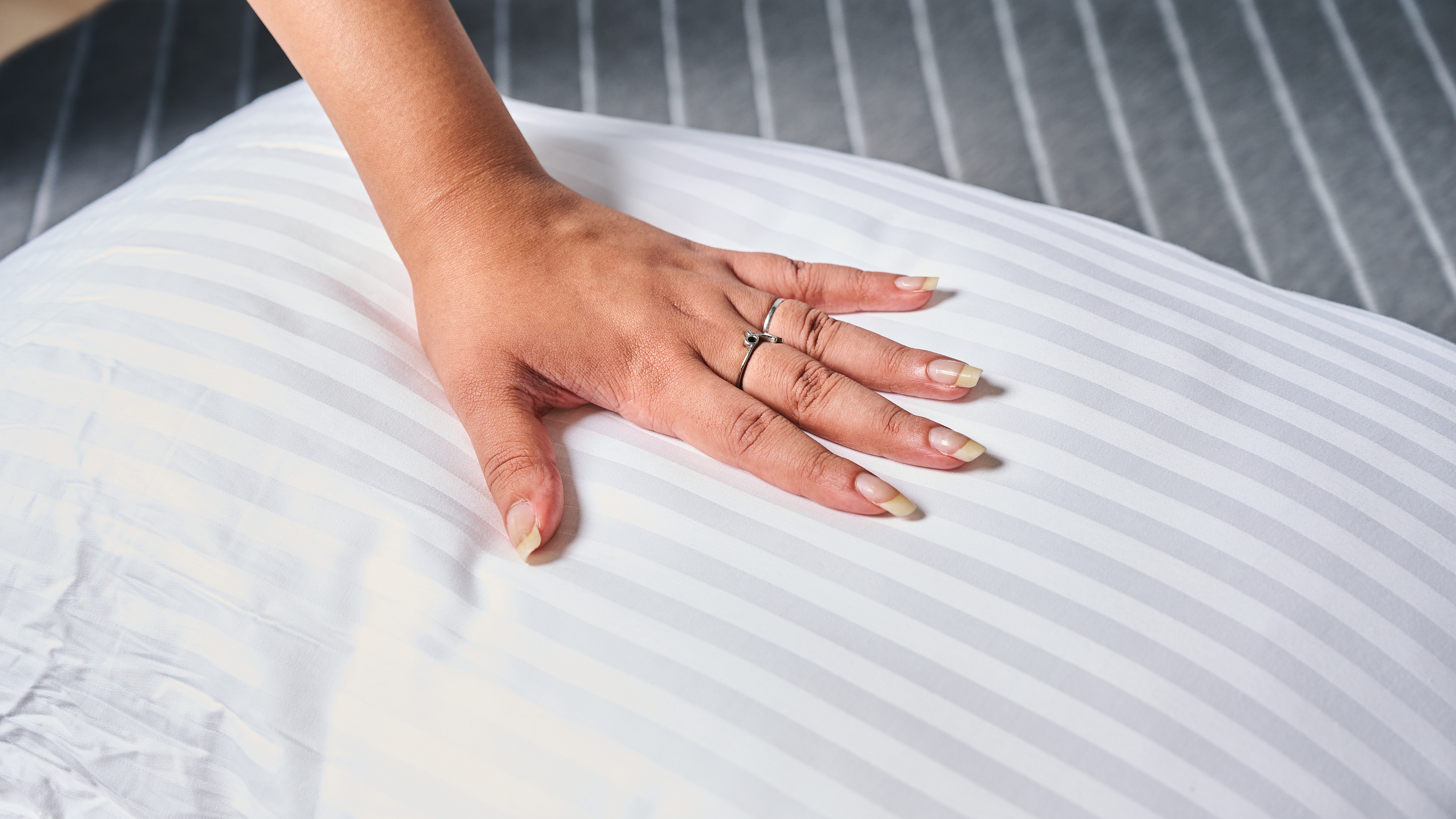 Hand placed on the surface of the Beckham Hotel Collection pillow to check temperature regulation