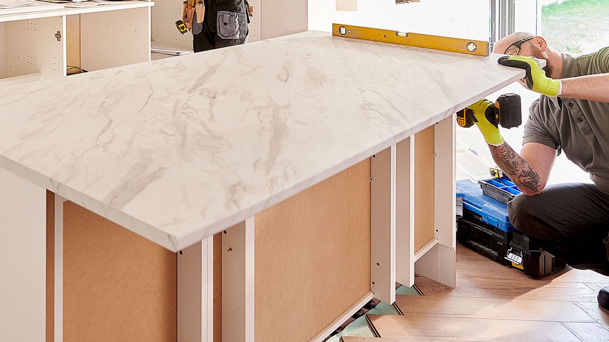 Man fitting marble effect worktop to cabinet