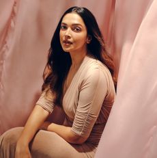 actress deepika padukone wearing a brown dress and posing as she's surrounded by blowing pink fabric