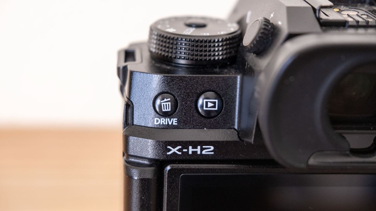 A close up of the drive button, gallery button and the X-H2 logo on the Fujifilm X-H2.