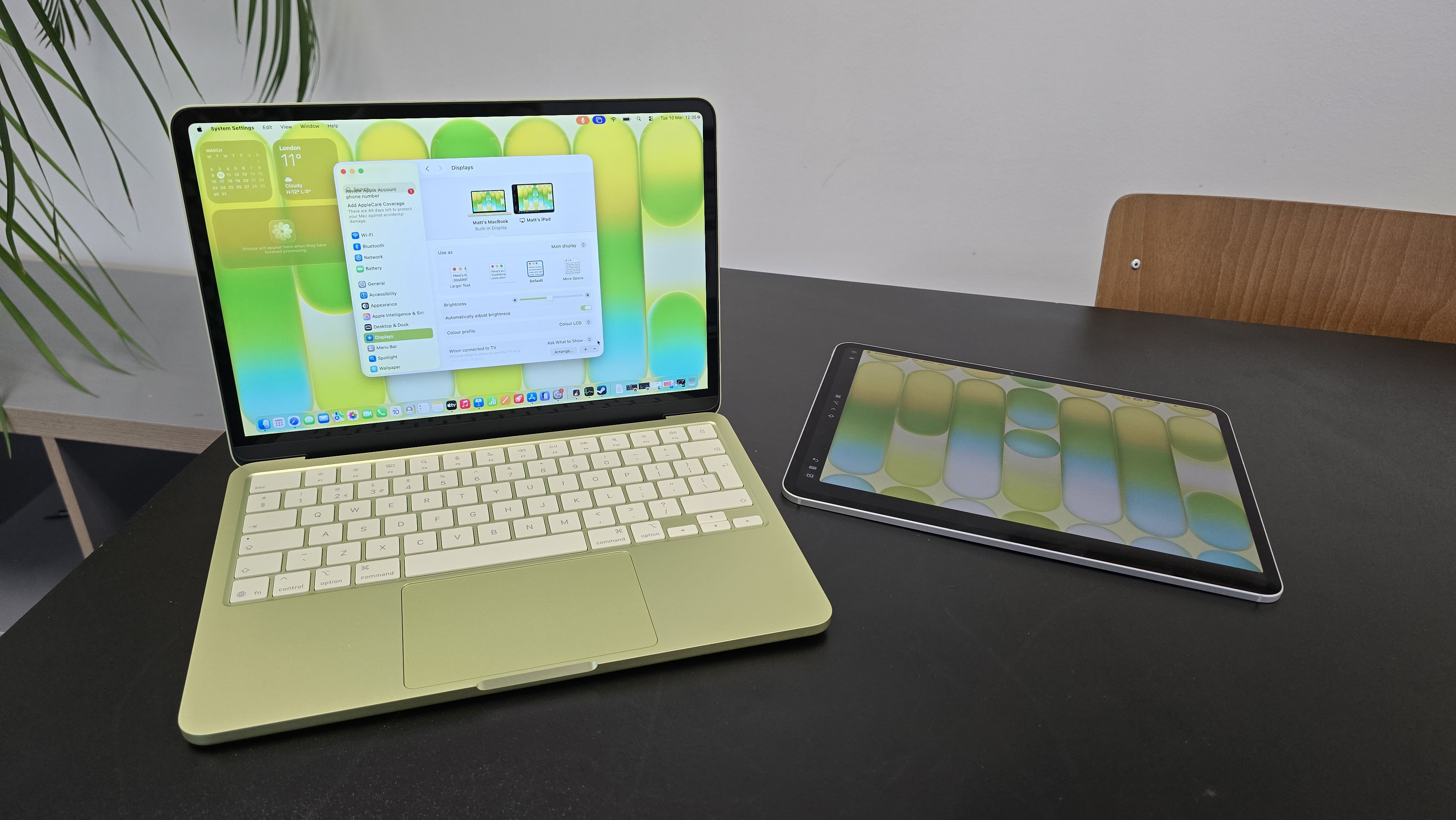MacBook Neo laptop on a desk with plant in background